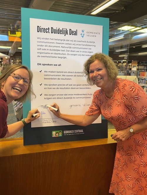 Derkje Veurink, directeur van gemeente Velsen en wethouder Marianne Steijn ondertekenen samen de Direct Duidelijk Deal