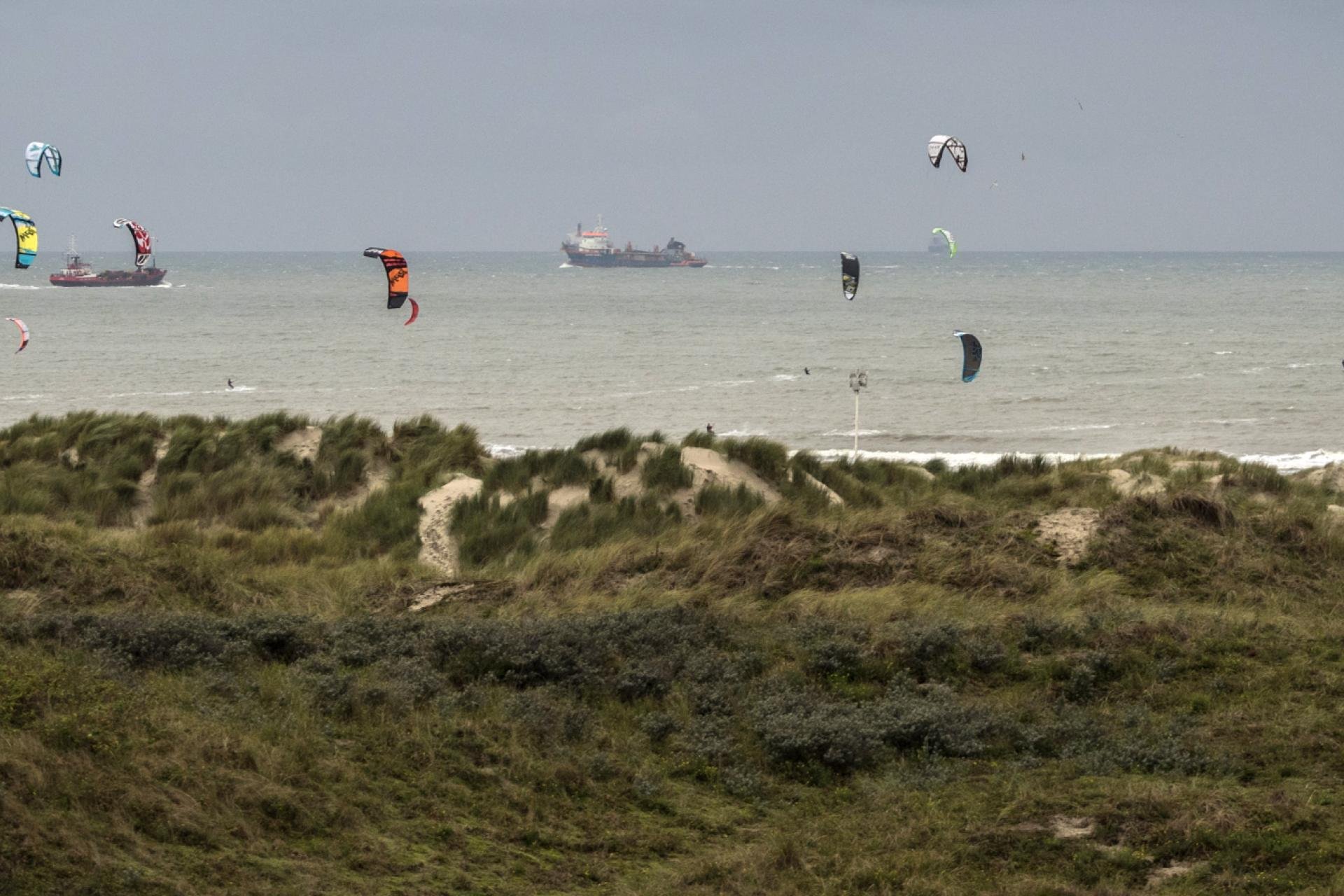 Kitesurfers op het strand en schepen
