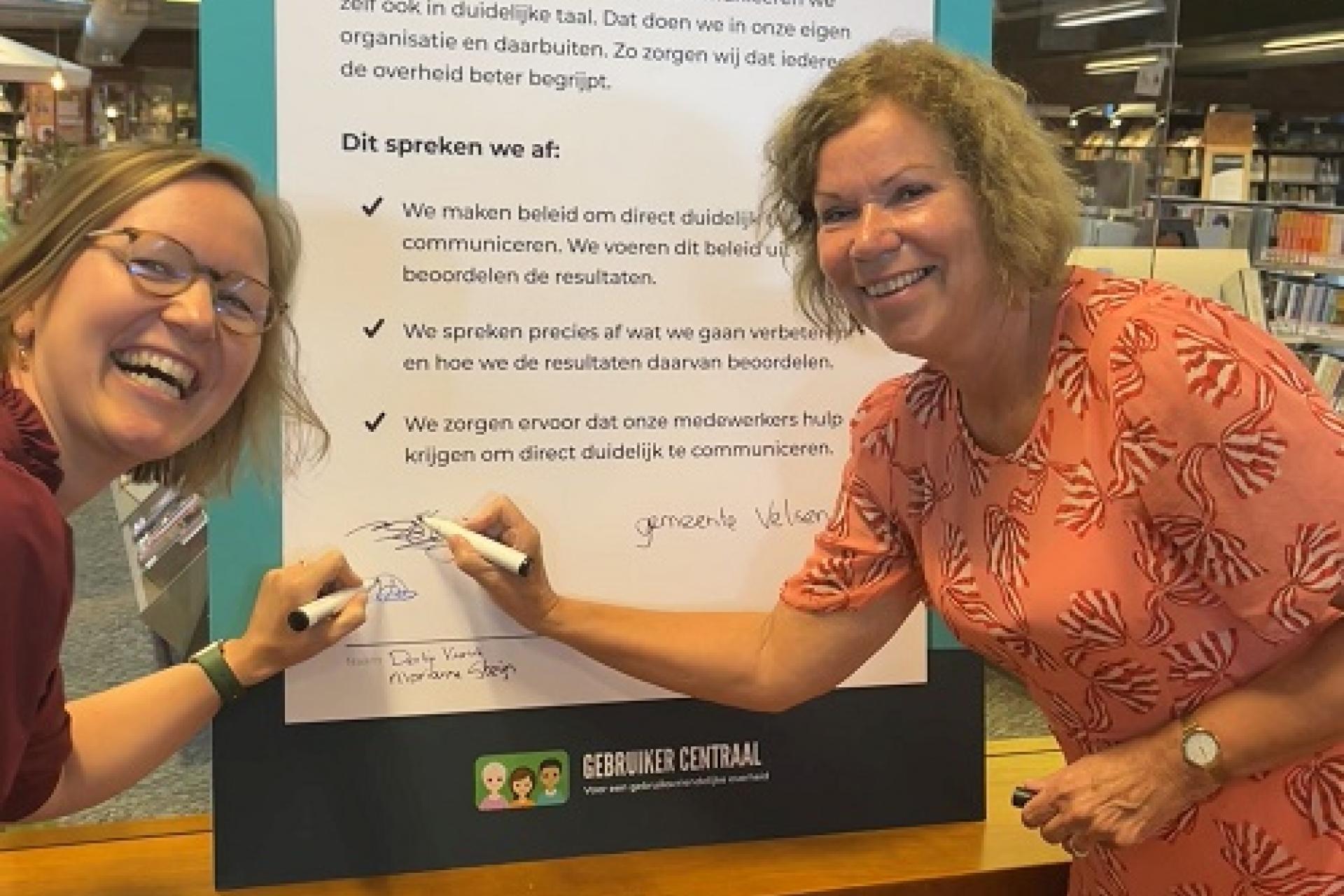 Derkje Veurink, directeur van gemeente Velsen en wethouder Marianne Steijn ondertekenen samen de Direct Duidelijk Deal