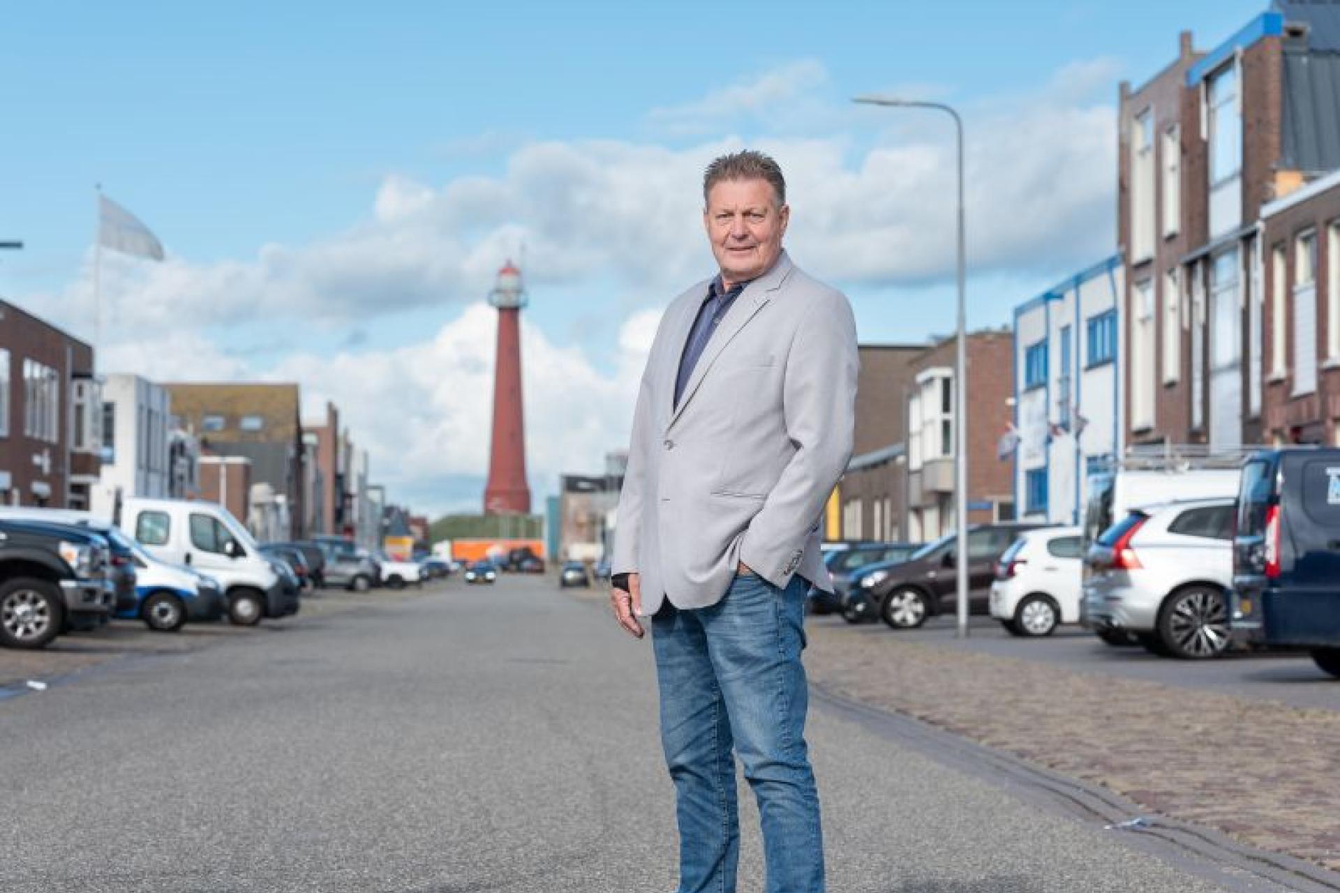 Leo Kwant staat middenin het havengebied van IJmuiden, de vuurtoren op de achtergrond