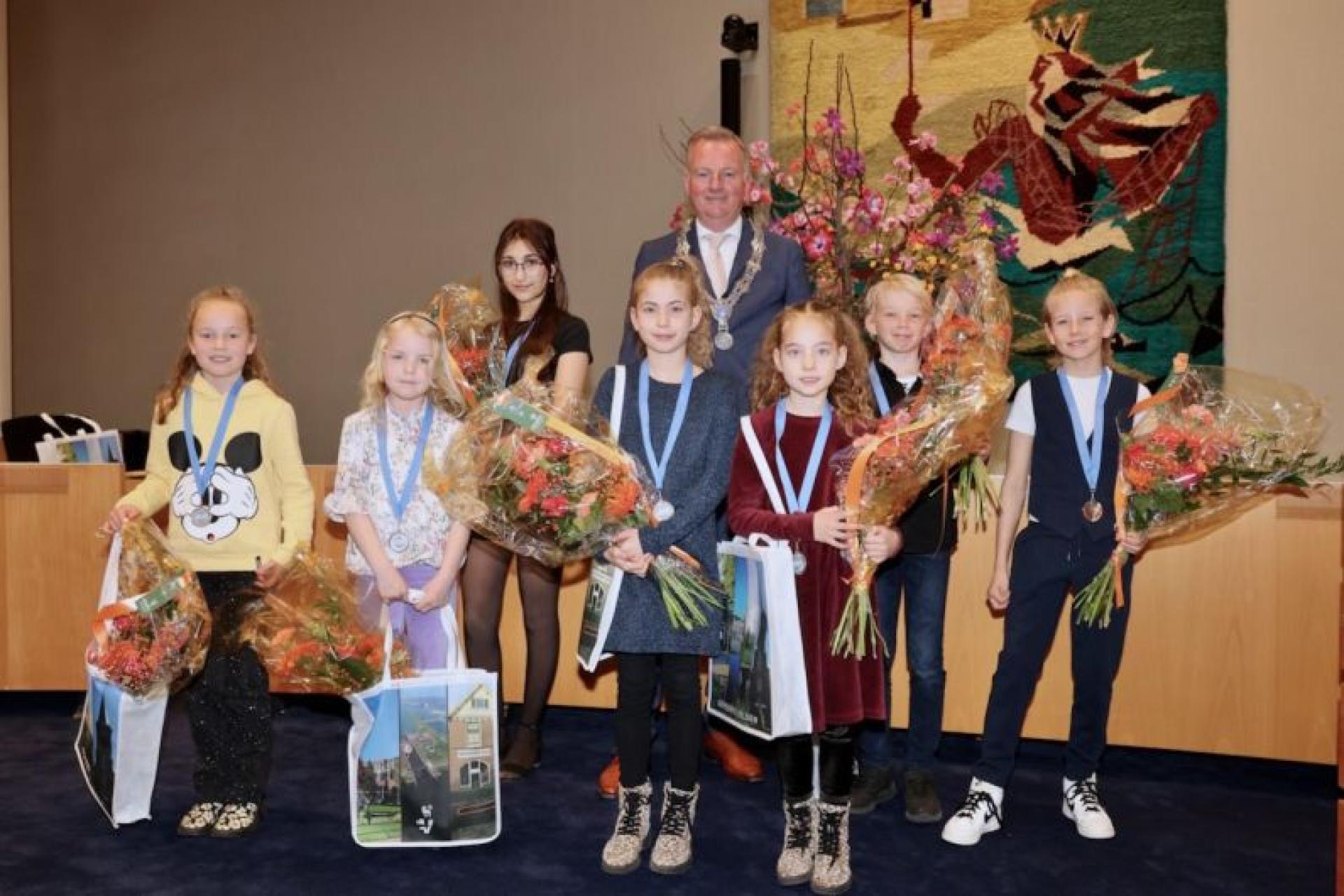 Groepsfoto winnaars jeugdlintje 2023 in de raadzaal met burgemeester Frank Dales
