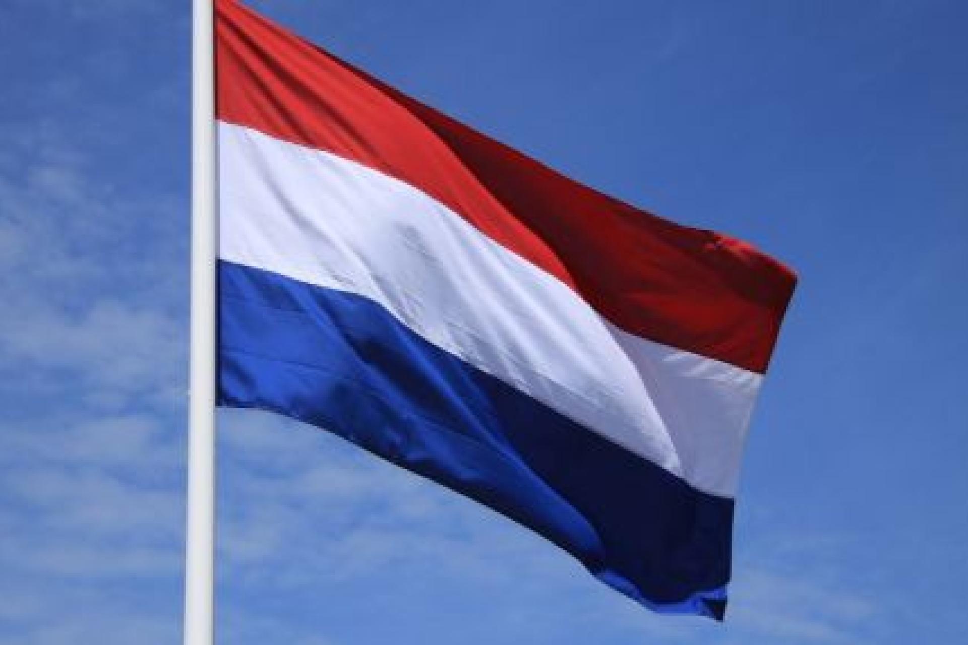 Wapperende nederlandse vlag met op de achtergrond een blauwe lucht