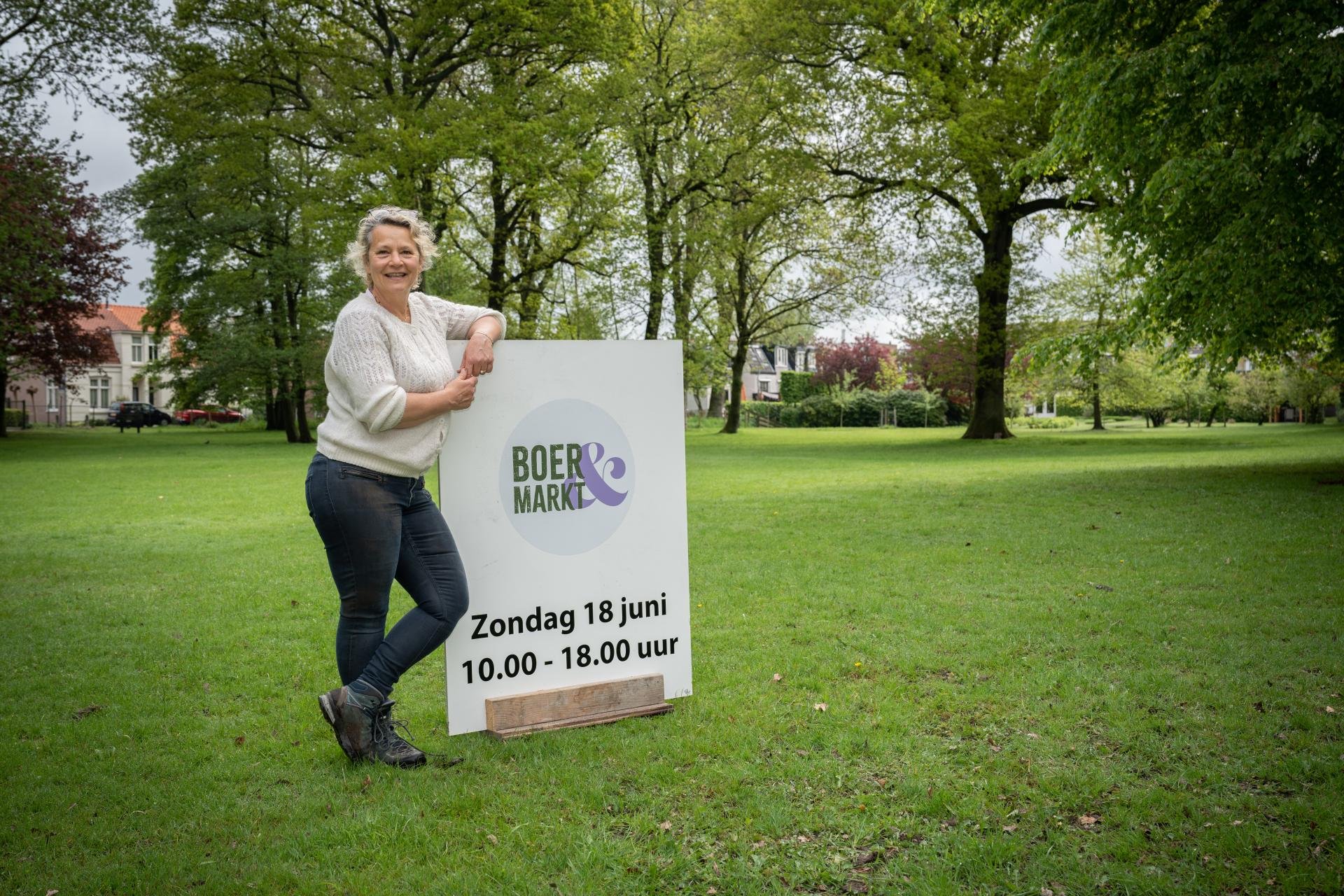 Brigitte Scholz staat met een bord van de Boer&Markt op het landje van Scholz