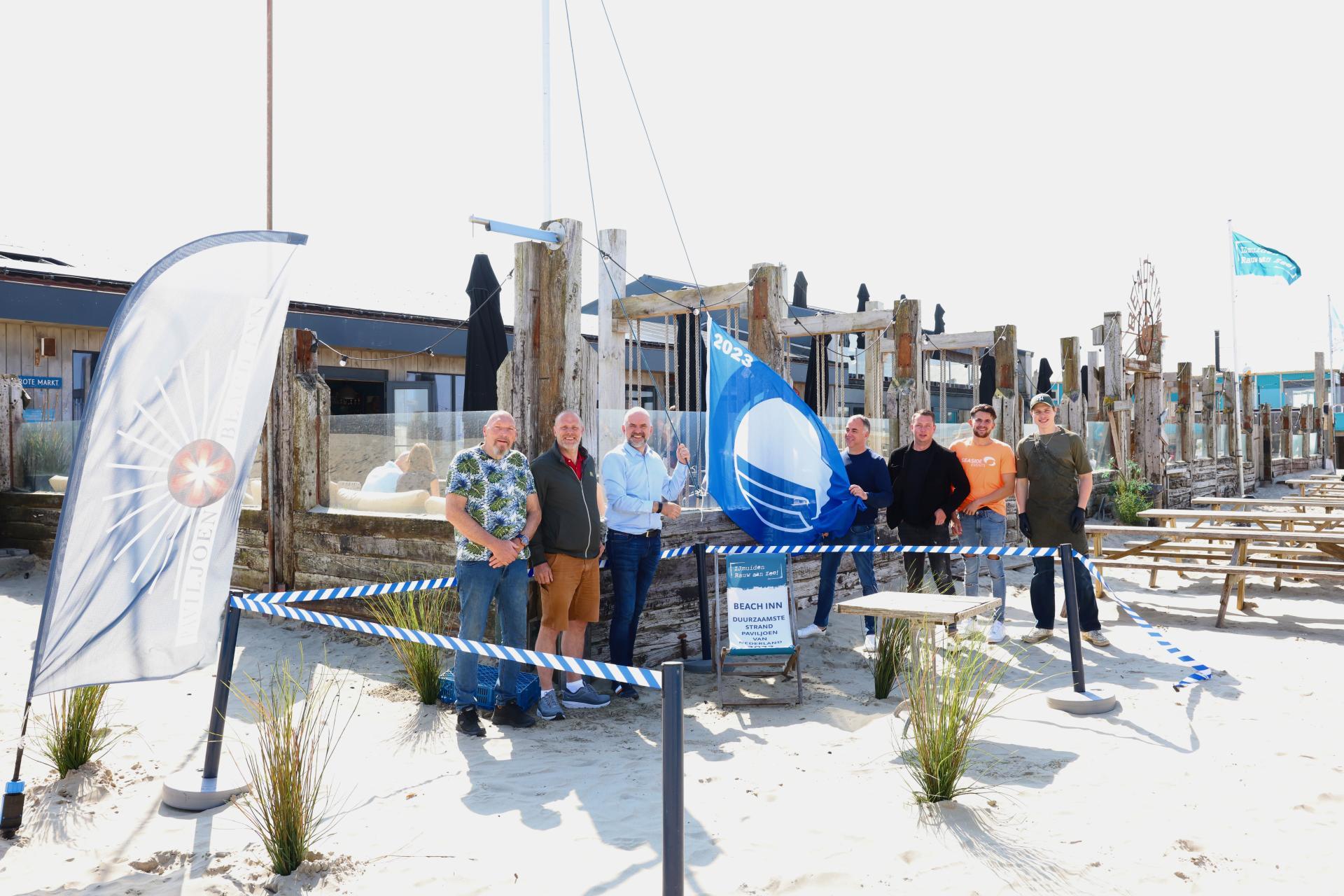 Wethouder Jeroen Verwoort hijst in IJmuiden bij paviljoen Beach Inn de blauwe vlag